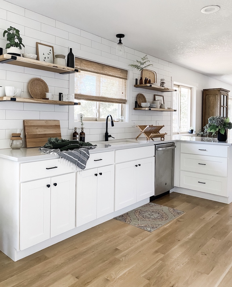 above the sink kitchen light with white cabinets and white subway tile