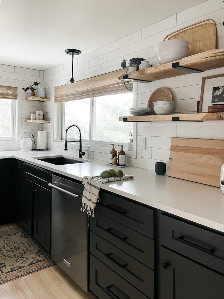black and white kitchen with wood shelves and woven window treatments