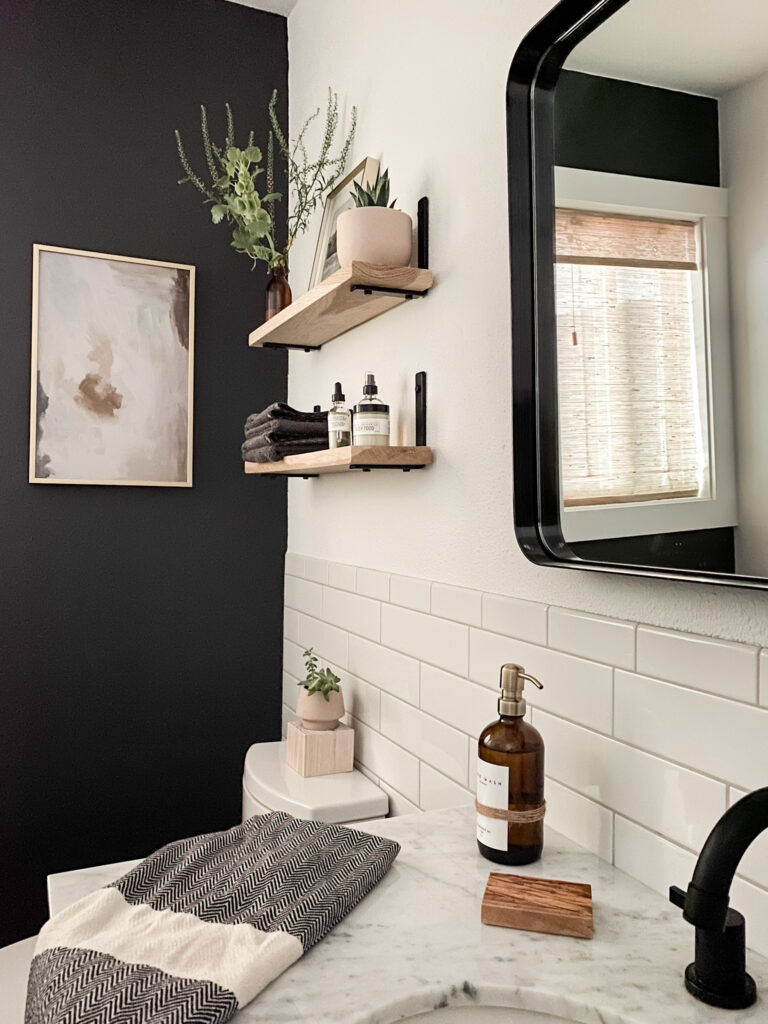 bathroom accent wall painted black and wood wall shelves above toilet