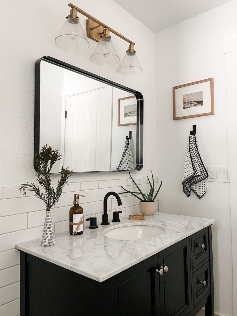 black and white bathroom with vanity, mirror, and vanity light