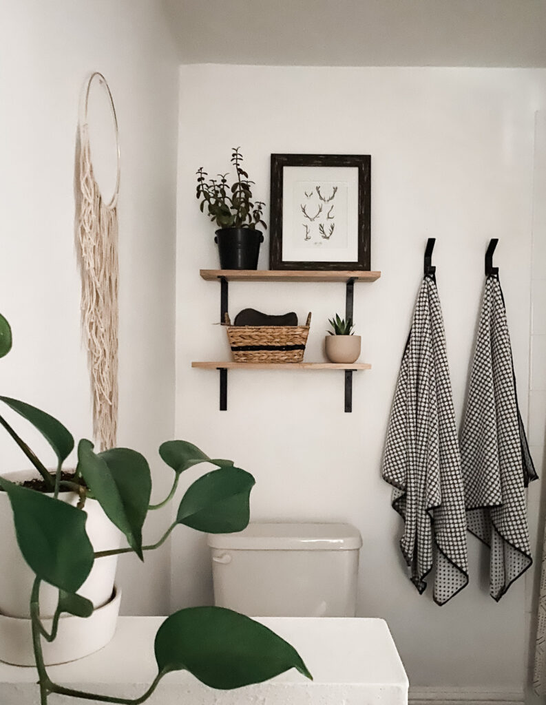 white bathroom with two wood shelves over the toilet