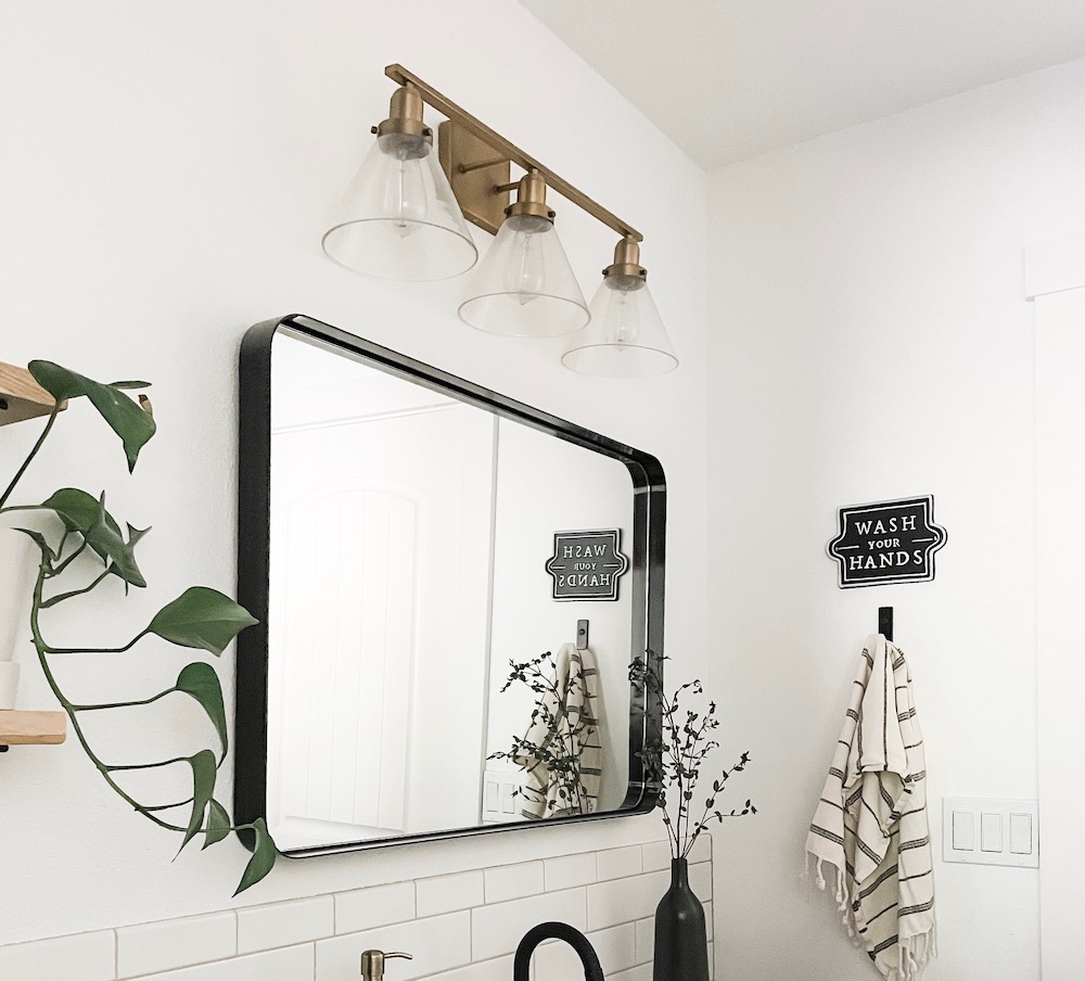 brass bathroom light fixture above mirror
