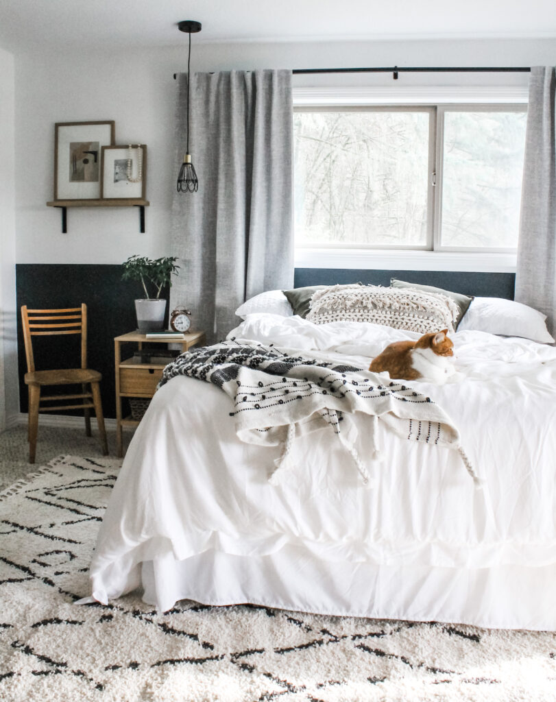 bedroom with boho details including textured blanket, tassel pillow, woven curtains