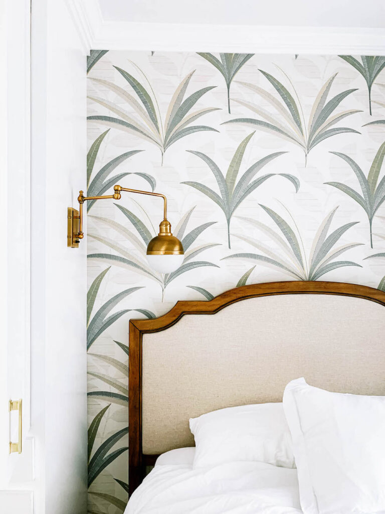 bedroom with palm wallpaper and brass sconce