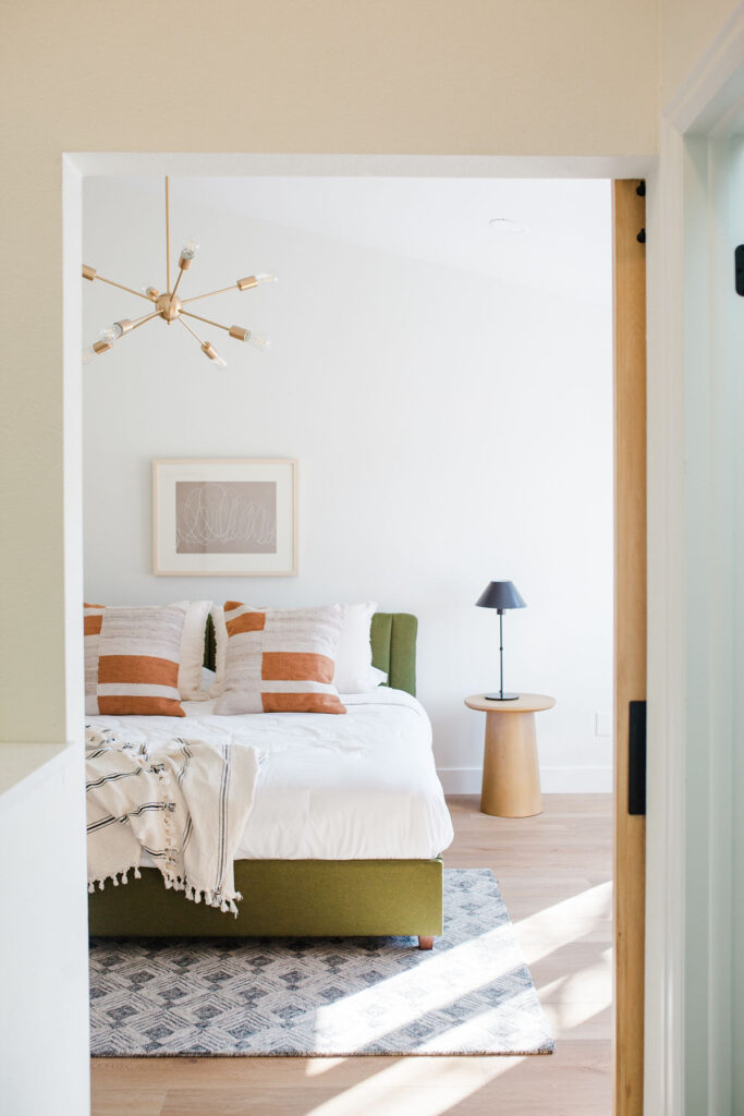 neutral bedroom home decor with some color on bed, pillows, and rug