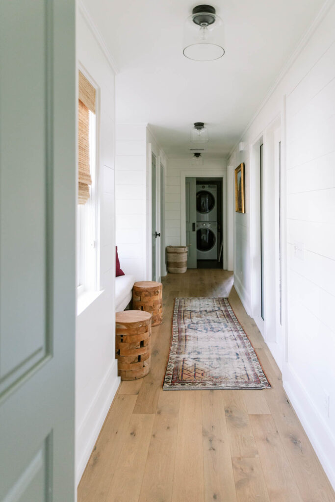 hallway with green door, rug, and stools