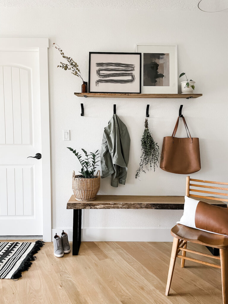entryway with wall hooks, bench, and artwork