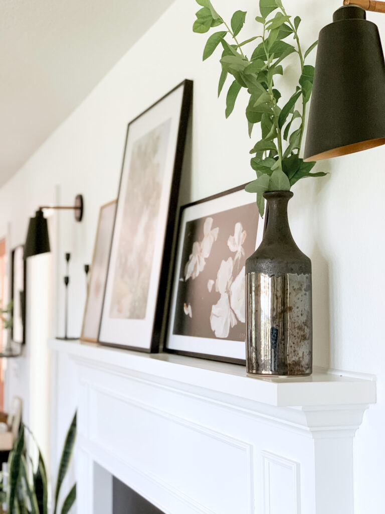 fireplace styling with artwork, vases, and sconces