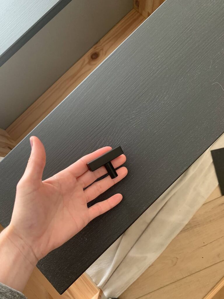 hand holding furniture pull for painted black dresser