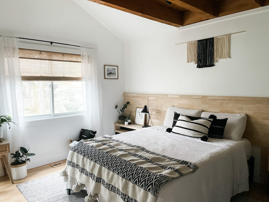 neutral bedroom with bed, rug, window treatments, pillows, and artwork
