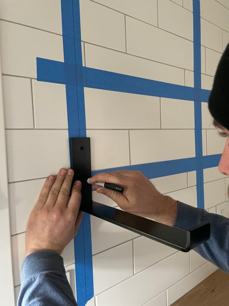 marking shelf bracket drill hole placement on white kitchen tile