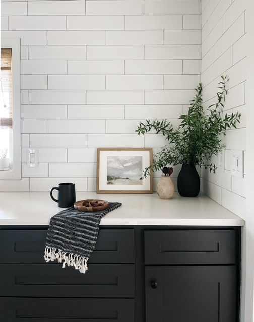 kitchen with black cabinets and white tile backsplash