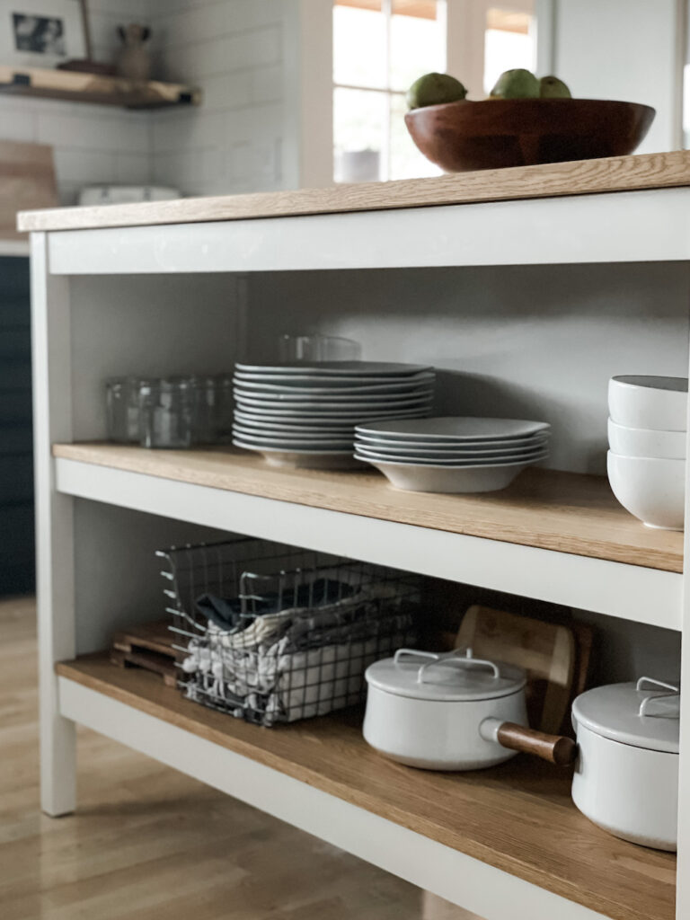 kitchen island styled with white plates, pans, and glasses