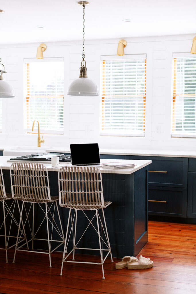 traditional kitchen with navy cabinets, white subway, and woven chairs