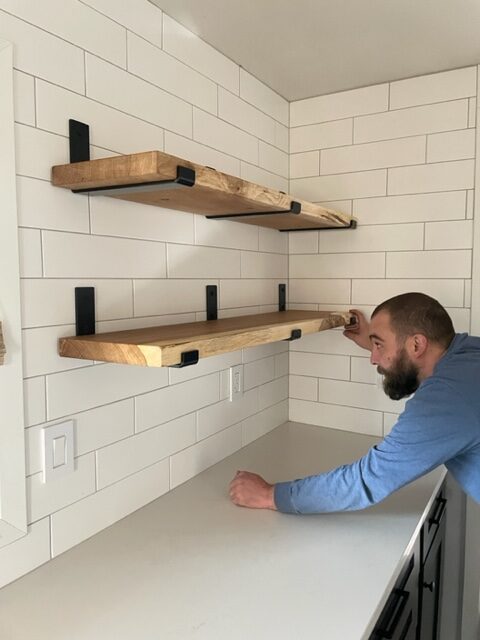 man installing wood shelves in kitchen