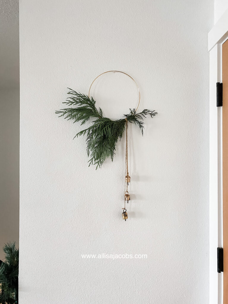 modern christmas wreath diy project with hoop, bells, and greenery