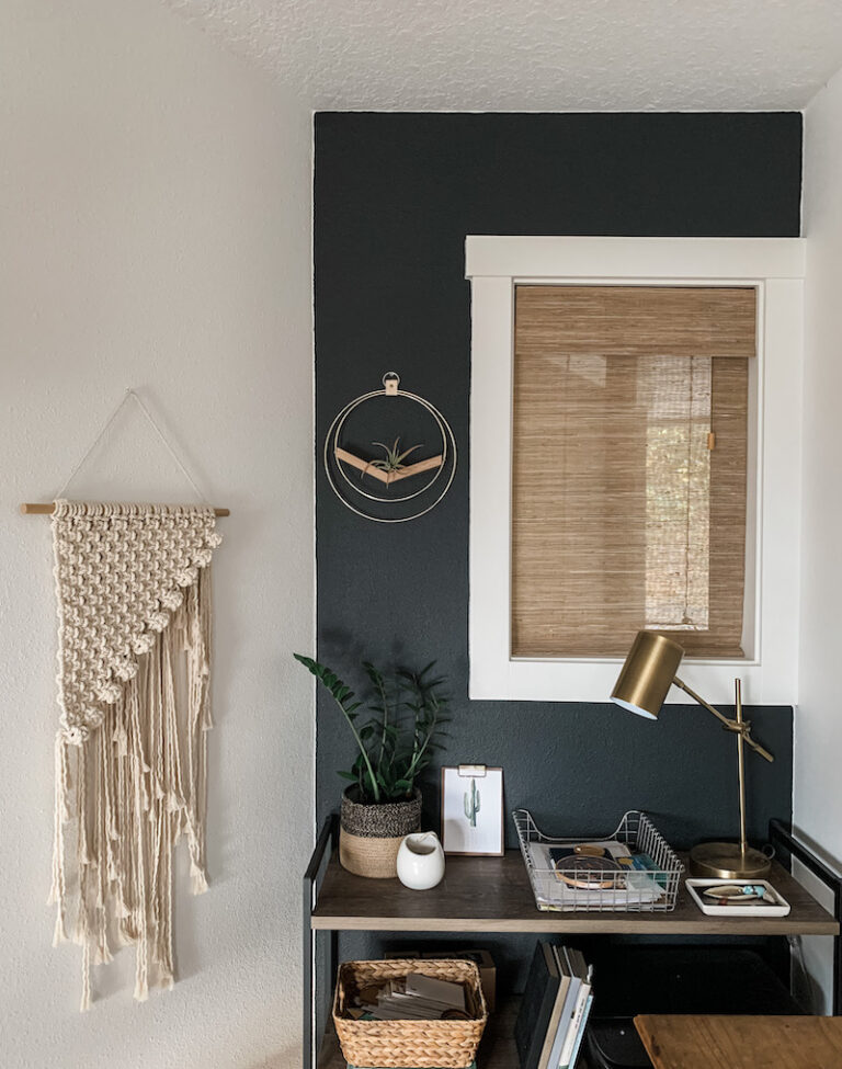 black wall with boho decor and window with woven shades