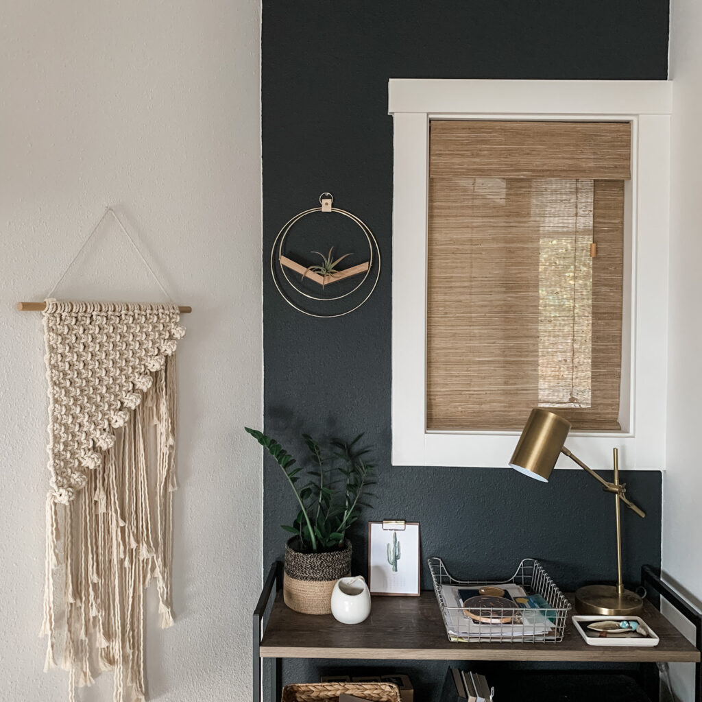 home office nook with black accent wall and woven wood window shades