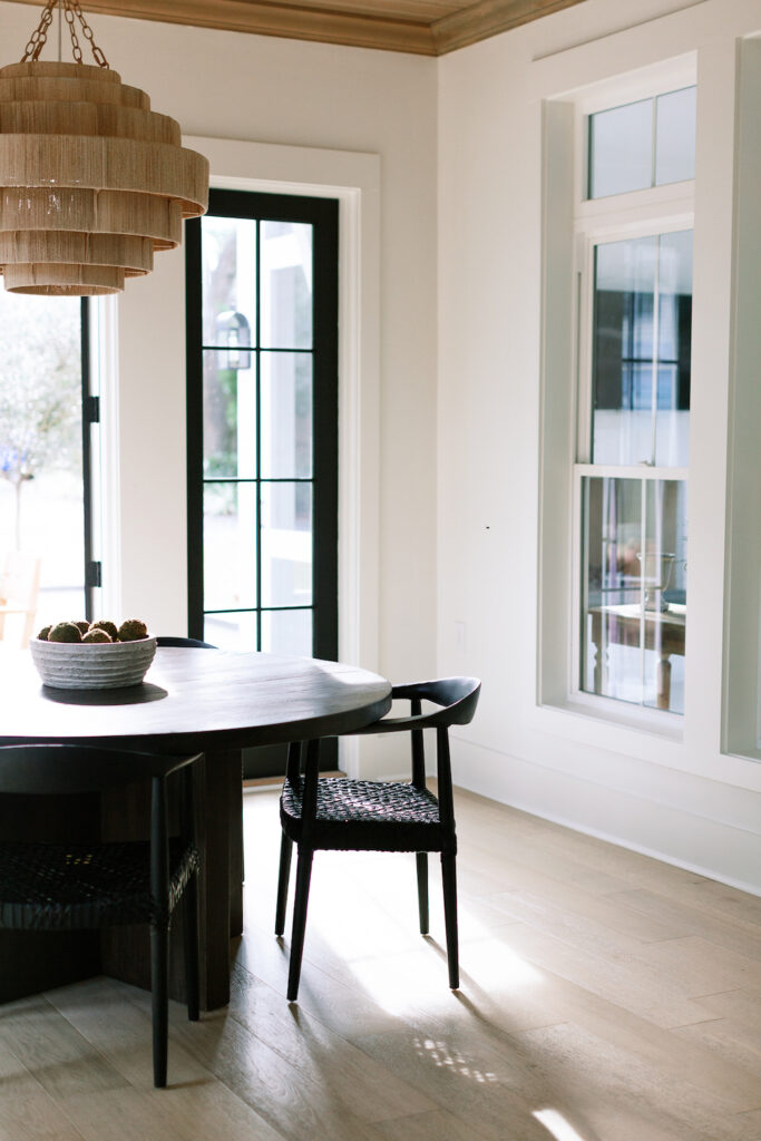 dining room with organic modern interior design with black table, woven chandelier, and wood floor