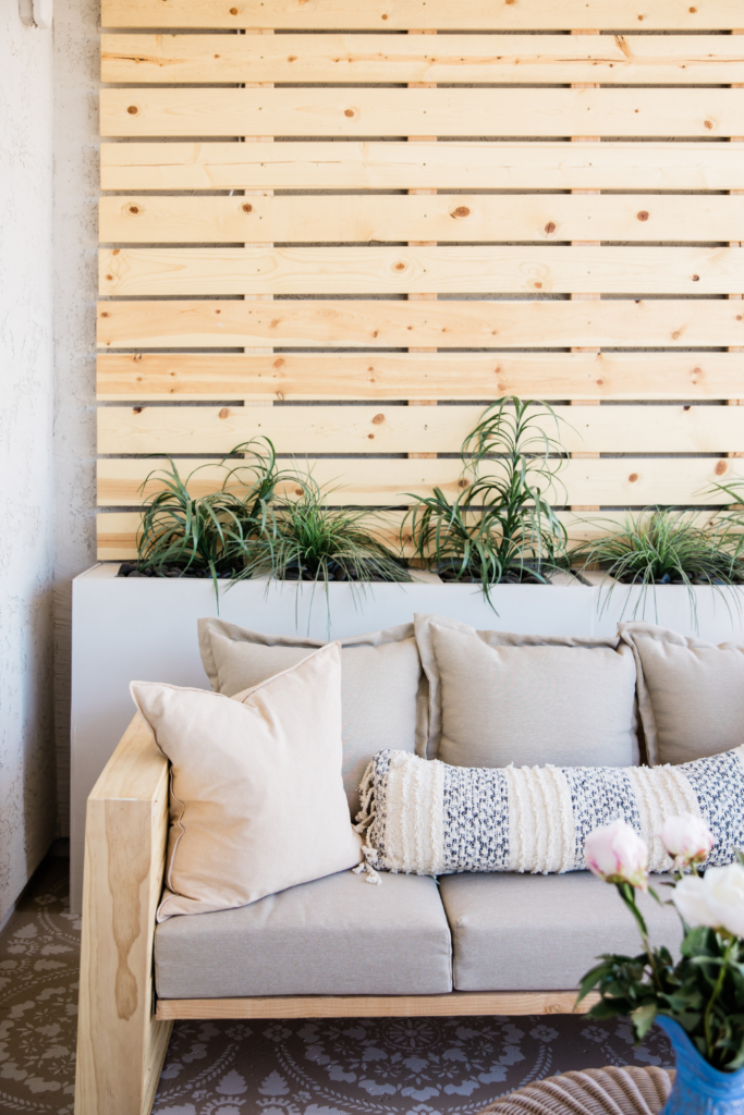 boho outdoor patio space with wood wall, plants, and throw pillows